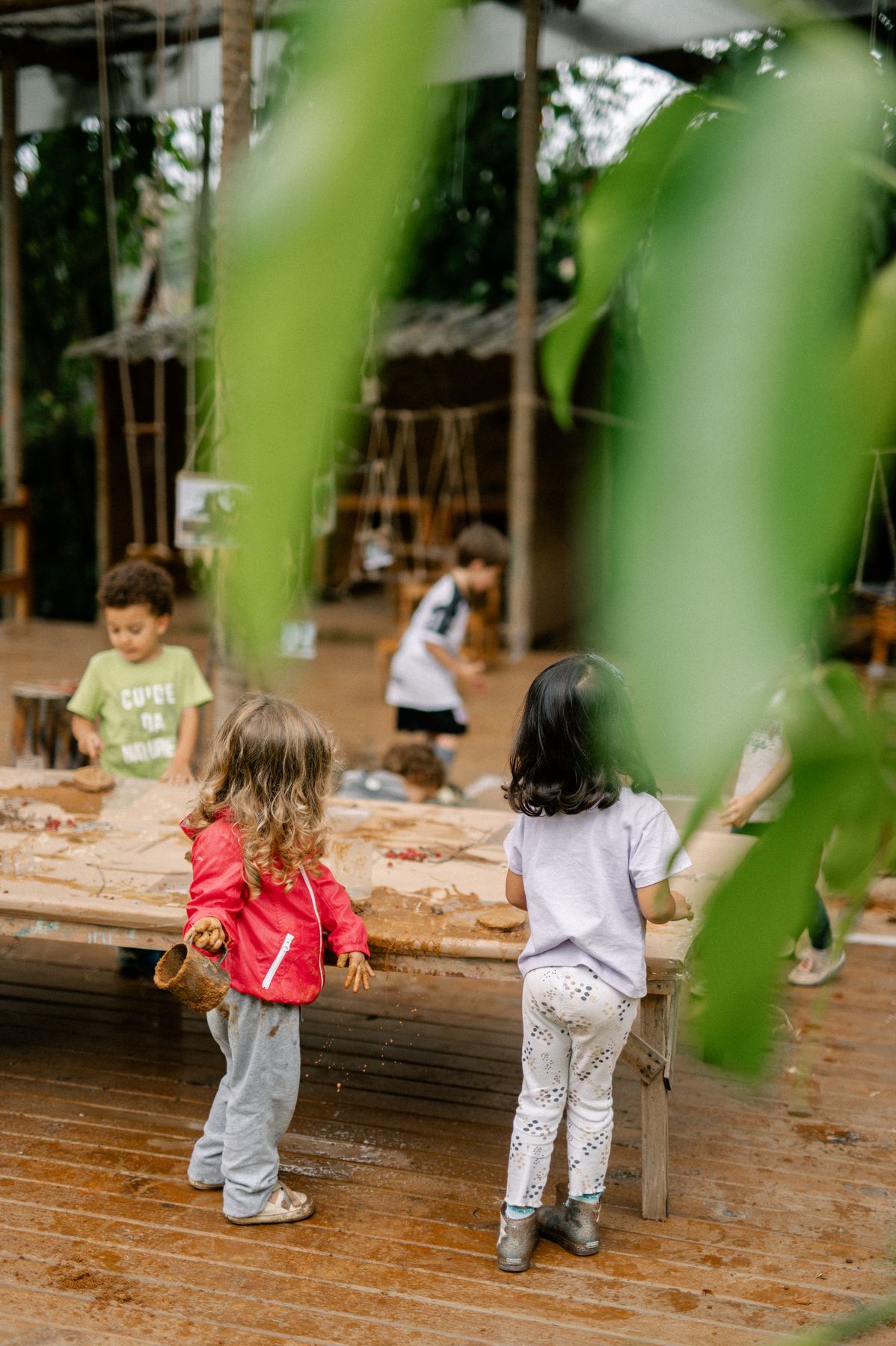 Crianças brincando com terra e água na área externa da escola